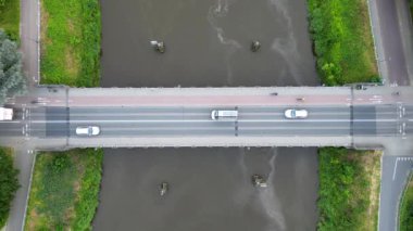 Tranquil River Crossing: Sahne Köprüsü ve akan sularla Hava Huzuru. Yüksek kaliteli 4K görüntüler, kendinizi bir an sükunetin içine daldırın bir köprünün büyüleyici hava görüntüsüne tanıklık ederken