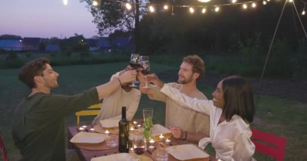 日没時にはテラスサマーパーティーで赤ワイングラスと一緒に応援を祝う若い友人の幸せなグループ 高品質4K映像 — ストック動画