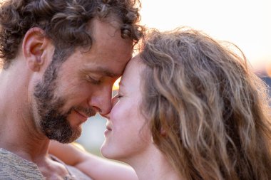 Birbirlerine aşık genç çiftler doğal bir günbatımı geçmişinde birbirlerine sarılırlar. Yüksek kalite fotoğraf