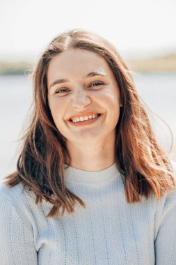 Genç, güneşli, heyecanlı, 20 'li yaşlarda turist bir kadın. Tişört giyip günlük kıyafetler takıyor kulaklık takıyor, deniz kenarında müzik dinliyor. İnsanlar hayat tarzı seyahat kavramını benimsiyor. Yüksek