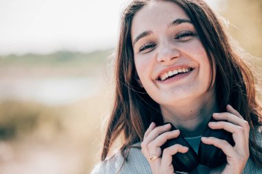 Melodik Bliss: Müzikal Zevkte Kaybolan Güzel Esmer 'in Yakın Çekim Portresi, kulaklıkla müzik dinleyen ve keyifle gülümseyen güzel bir esmerin portresi. Yüksek
