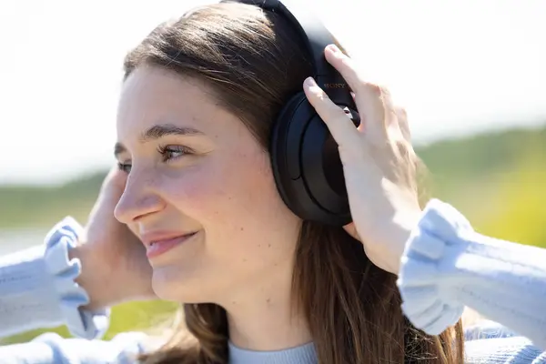 Experience the captivating sight of a pretty and attractive young millennial woman immersed in her world of music, courtesy of wireless headphones. Her serene face reflects the pure joy of nature and