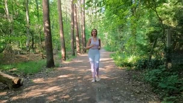 若くて決まったフィットネス愛好家に加わり 緑豊かな森の中を爽快に走り出します このスローモーションビデオは 健康的なライフスタイルへの彼女のコミットメントを示しています — ストック動画