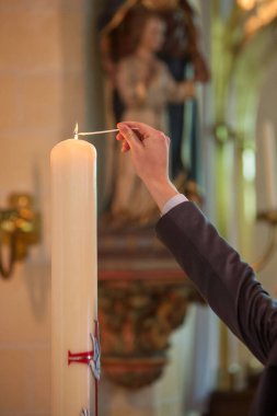 Kiliselerin dingin atmosferinin resmi kucaklamasında, bir erkek el nazikçe uzanıyor, Paskalya mumlarını yakıyor kutsal alev. Bu sonsuz an umudun ve inancın yenilenmesini simgeliyor.
