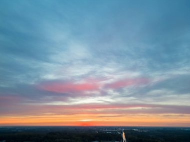 Güneş ufkun altına batarken, gökyüzünde canlı renkler bırakırken nefes kesen doğa tuval dramasını izleyin. Bu hava görüntüsü bir güneşin doğuşunu ya da günbatımını bir gökyüzünün altında canlı renkler olarak yakalar.
