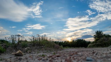 Doğadaki toprak bir yola çok düşük açılı bir perspektif. Yol ileri doğru uzanıyor, ufka doğru bakıyor, büyüleyici mavi bir günbatımı gökyüzünün altında huzurlu bir resim çiziyor.