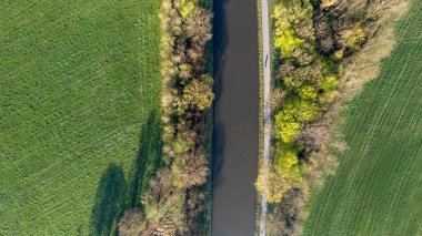 Çayırların yemyeşil çayırlarında süzülen sakin bir nehir ya da kanal manzarası ve ormandaki ağaçların huzur dolu kucaklaması. Ağaçlar ve Meadows arasındaki Aerial Nehri. Yüksek kalite