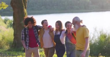 Dostluğun sembolleri. Etnik çeşitliliğe sahip bir grup insan, bir çayırın ormanlık gölünde kol kola, omuz omuza yürüyorlar ve eklem ellerini havaya atıyorlar. İnsanlar arasında eşitlik. Yüksek