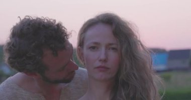 Romantik ve şehvetli bir an genç heteroseksüel bir beyaz çift tutkuyla sarılır, öper ve günbatımının sıcacık arka planından zevk alır, aşkın özünü yakalar ve