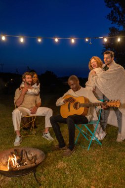 Genç hipster 'lar kamp alanında birlikte müzik yemekten ve içmekten keyif alıyorlar. Tatil hayatı ve gençlik kültürü konsepti. Mutlu arkadaşlar grubu barbekü kampı partisinde bira içiyor.