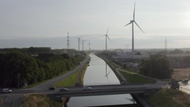 Kuşbakışı bakış açısı, doğa ve sanayinin iç içe geçtiği bir sahneyi gözler önüne serer. Bir insan koşuşturması damarı olan köprü, aşağıdaki sakin nehir suları üzerinde amansız bir trafik akışı taşır. Bitişik,