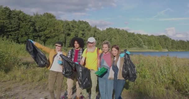 在这个令人振奋的慢镜头中 一群千百年来的朋友正在准备清理森林湖岸 他们装着垃圾袋 随时准备恢复自然 — 图库视频影像