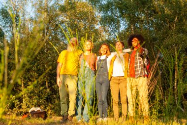 Bu yüksek kaliteli fotoğraf, altın saat boyunca doğanın büyüleyici güzelliğinin ortasında duran çeşitli, çok ırklı bir grup arkadaşın durduğu huzurlu bir anı yakalıyor. Güneş sıcacık, büyüleyici