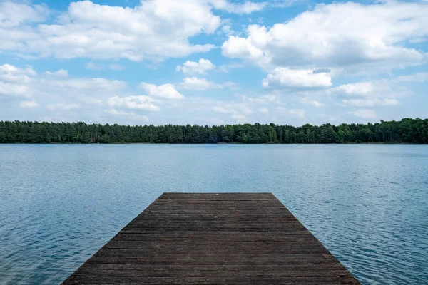 stock image This image presents a tranquil wooden dock leading out to a calm and expansive lake. The simplicity of the composition, with the wooden platform jutting into the water, invites contemplation and a