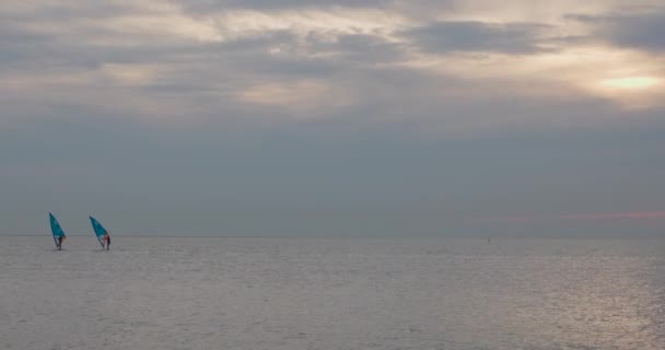 画面中仍然是大海在黄昏时的广阔宁静 冲浪者逐渐从画面中走出 离开了浩瀚静谧的大海 一幅柔和的夜晚色彩的帆布 — 图库视频影像