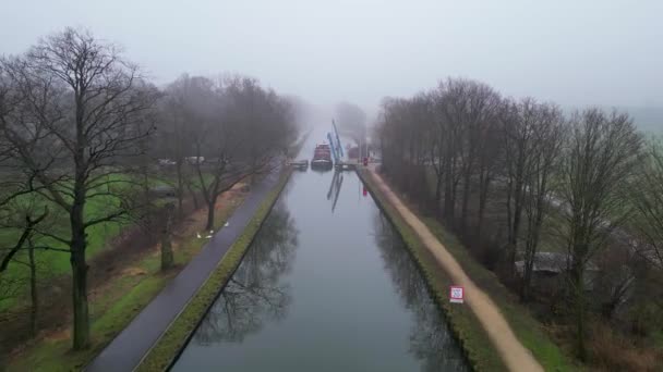 镜头展示了一条笼罩着薄雾的运河的空中景观 营造出一种宁静而略显神秘的氛围 这条运河的侧边是一排排平行的光秃秃的树 它们的枝条伸向下游 — 图库视频影像