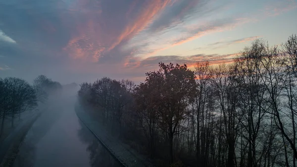 Şafak sökerken, sisli bir kanal güneşin doğuşuyla hafifçe aydınlanır ve sakin bir manzara yaratır. İlk ışık, sabah sisinin içinden süzülerek suların yüzeyine yayılır ve...