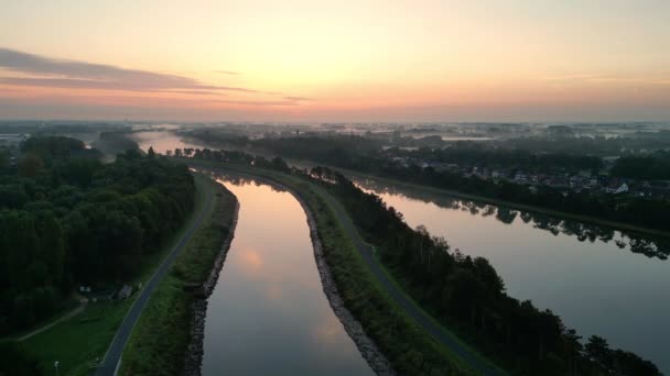 一幅全景的画面揭示了黎明时分雄伟蜿蜒的河流 清晨的阳光沐浴在柔和温暖的阳光中 从平静的水面上反射出 从远处的城镇里透出灯光 — 图库视频影像