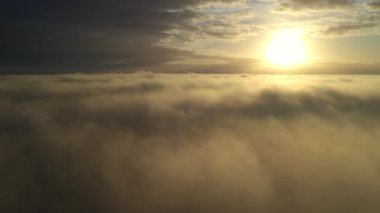 Görüntüler bulutlardan oluşan bir battaniyenin üzerinde nefes kesici bir an yakalıyor, güneşin doğuşu dramatik bir manzara yaratıyor. Güneş, alev alev yanan bir küre, gökyüzünde sarkıyor, aydınlatan altın bir parıltı
