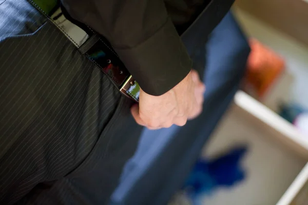 The photograph captures a close-up view of a person in professional attire, possibly a law enforcement officer, discreetly securing a hand on their service weapon holstered at their side. The focus on