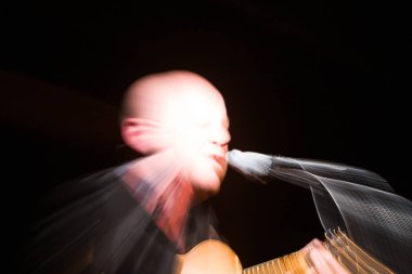 Bu dinamik görüntü hareketli bir müzikal performansın özünü yakalar. Sanatçı, hızlı hareketle bulanıklaşır, gitarı ve mikrofonuyla meşgul olur, enerji ve...