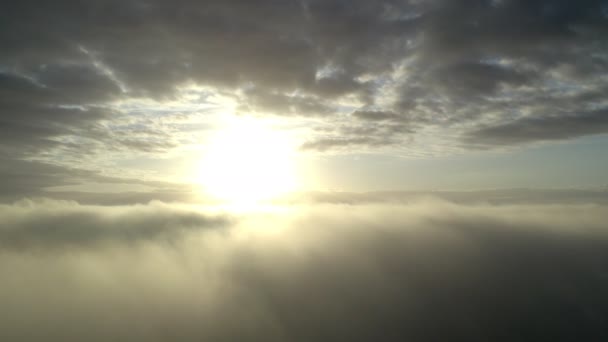 白い雲を動かす青い空の景色を眺める ドローンは 明るい太陽の朝のふわふわした雲を通って青空にハイバックします 太陽は雲の後ろに隠れて霧を日の出に — ストック動画