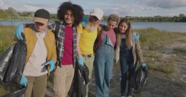 Bu ilham verici görüntü, göl temizleme çalışmalarına katılarak çeşitli görünümlerde ve bilerek birleşmiş bir grup genç gönüllüyü yakalıyor. Eldiven ve çöp torbalarıyla donatılmışlar.