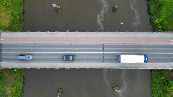 这个自上而下的静态镜头记录了车辆每天通过水上桥梁的通勤情况 俯瞰的景色强调交通的线形运动 中间点缀着水面上的波纹 — 图库视频影像