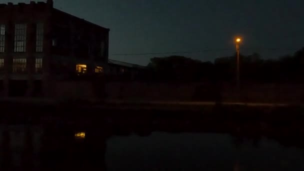 このパンニング映像は ウォーターフロントに沿って昼から夜への静かな移行を捉え 夕暮れの光が柔らかく建築と水を照らしています シルエット — ストック動画