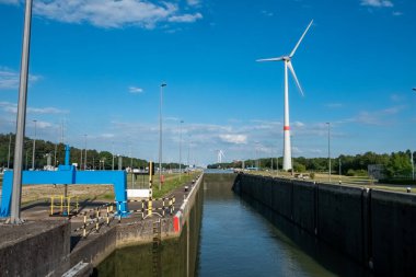 Bu canlı görüntü, açık bir günde yüksek rüzgar türbiniyle sürdürülebilir enerjinin zeminine karşı kurulmuş bir deniz kilitlenme sistemine sahip. Kilitler yönetim için kritik bir altyapı görevi görüyor