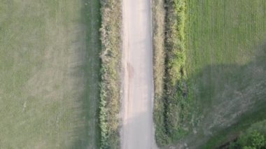 Yukarıdan çekilen bu görüntüler, pastoral bir ortamda basit bir toprak yol kesişmesini gösteriyor. Çayırların ve ağaçların verimli yeşillikleriyle çevrili bu iki yol, seçenekleri ve sessizliği akla getiriyor.