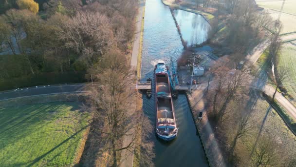 这是空中的脚踏船 展示了一艘驳船在一条狭窄的运河中漂浮 经过一座吊桥 两边都有平行的道路 低角的太阳投下的阴影表明 — 图库视频影像