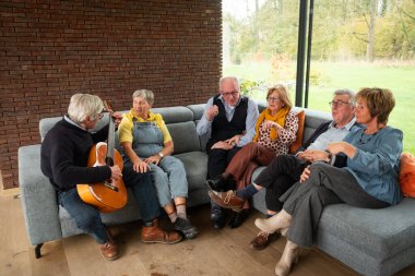 Açık hava manzarası sunan geniş pencereli rahat, iyi ışıklandırılmış bir odada, bir grup son sınıf öğrencisi bir müzik zevkini paylaşıyor. İçlerinden biri klasik bir akustik gitar çalıyor.