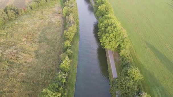 田舎の穏やかな運河に沿った平和な空中旅 この無人機の映像は 牧歌的な静けさの本質を捉えています 活気に満ちた緑の木に囲まれた運河 — ストック動画