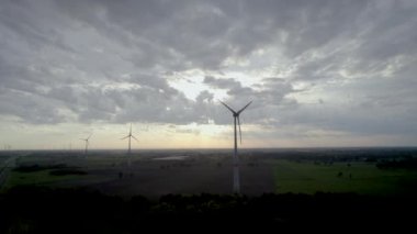 Alacakaranlık karaya inerken, bu stok görüntüler rüzgar türbinlerinin heybetli siluetlerini yakalıyor, yenilenebilir enerji devlerini, manzaranın üzerinde yükselen. Karanlık gökyüzü, resmedilmiş