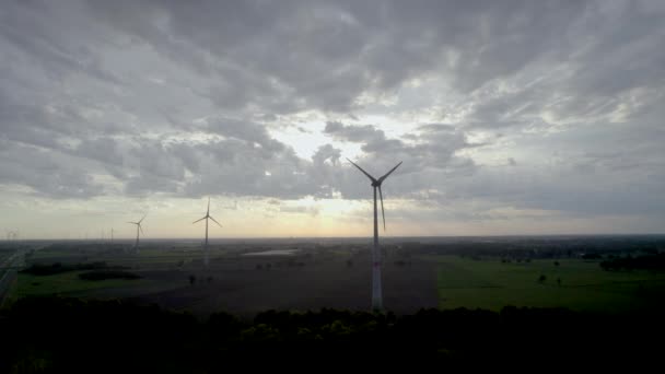 夕暮れが陸に降り立つにつれて このストック映像は風力タービンの強烈なシルエット 再生可能エネルギーの巨人 風景の上にタワーを張っています 暗い空が描かれている — ストック動画