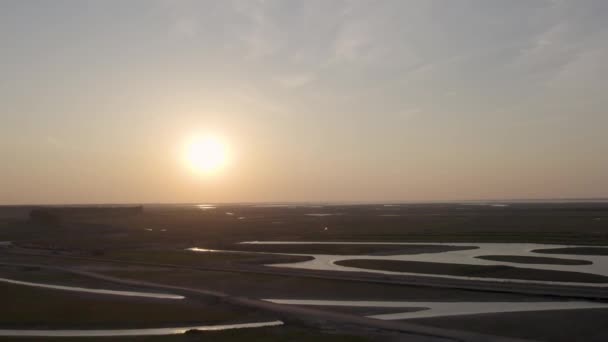 このストック映像は 夕日の暖かさを反映した水路を備えた工業的な風景の上に日没の穏やかな景色を提供しています 空中視点は その対比を強調する — ストック動画
