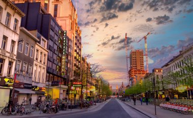 Antwerp, Belçika, 23 Mart 2019 'da bu görüntü, Antwerp' teki De Keyserlei 'yi gündüz karanlığa geçerken yakalar. Batan güneş, binaların ön cephelerinde sıcak bir parıltı saçar.