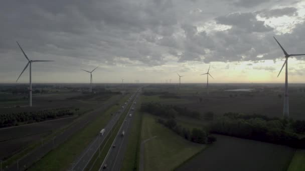 このストック映像は 伝統的な旅行と現代の再生可能エネルギー源の交差点を象徴する 賑やかな高速道路の上に立っている風力タービンの強力なシーンをキャプチャします として — ストック動画