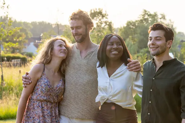 This warm and engaging photograph showcases a group of four friends enjoying each others company during a beautiful sunset. The group is diverse, featuring individuals of different ethnicities, and