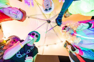 Bu canlı fotoğraf renkli kostümler giymiş bir grup arkadaşı resmediyor ve şenlikli bir toplantının keyfini çıkarıyor. Düşük bir açıdan bakıldığında, görüntü bir neşe ve neşe duygusu taşır.