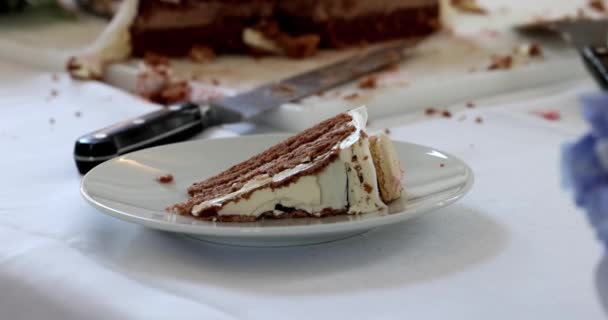 このスローモーション映像は ケーキの残りとサービングナイフで白いプレートで提供される層状チョコレートケーキの完璧なスライスの豪華な瞬間をエレガントに捉えます — ストック動画