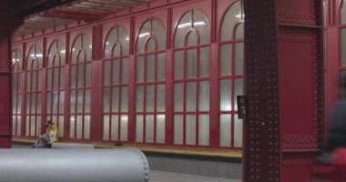 Bu görüntü, Antwerp Merkez İstasyonu platformu boyunca yürüyen yolcuları görüntüler. İnsanların hareketi, iç kısımdaki ikonik kırmızı sütunlara ve kemerlere karşı koyuyor.