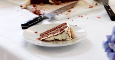 Bu stok görüntüsü beyaz bir tabakta servis edilen bir dilim çikolatalı pastayı yakalıyor, arka planda pasta bıçağı ve kırıntılar yakın zamanda keyifli bir tatlıyı işaret ediyor. Sahne hazır.