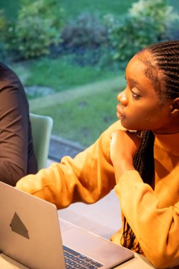 Görüntü, profesyonel bir toplantı ya da planlama sırasında derin düşüncelere dalmış Afrikalı Amerikalı bir kadını gösteriyor. Bakışları kameradan uzak bir yere bakıyor, muhtemelen...