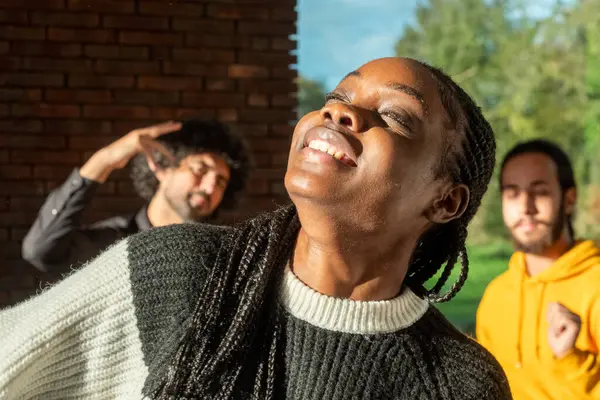 In a room bathed in the warm light of the sun, an African American woman is the picture of exuberance, her head thrown back in laughter, embodying a moment of pure joy and liberation. Her braided