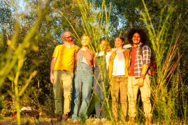 Bereketli yeşilliklerle çevrili gülen arkadaşlar, güneşin sıcaklığında güneşleniyorlar. Güneş Işığı Doğası 'nda Arkadaşların Gülüşü. Yüksek kalite fotoğraf