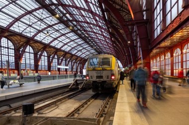Antwerp, Belçika, 25 Ocak 2024, Antwerp Merkez İstasyonu 'nda tren kalkışa hazır ve banliyö yolcuları platformda hızla yürüyen tipik bir geceyi özetliyor. Teklif