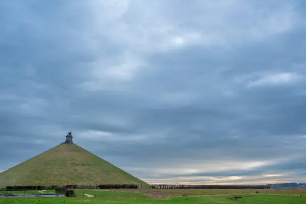 stock image This evocative image captures the iconic Lions Mound, a conical artificial hill topped with a lion statue, located at the historic Battlefield of Waterloo in Belgium. The monument, commemorating the