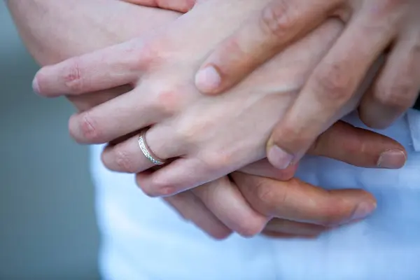 这是一张特写照片 它将一对情侣的手紧紧地握在一起 把焦点集中在一枚钻石戒指上 这意味着他们做出了深刻的承诺 这张照片唤起了一种亲密感 — 图库照片